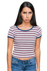 Fototapeta premium Young hispanic girl wearing casual striped t shirt depressed and worry for distress, crying angry and afraid. sad expression.