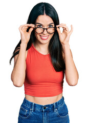 Obraz na płótnie Canvas Young hispanic woman wearing casual clothes and holding glasses smiling with a happy and cool smile on face. showing teeth.