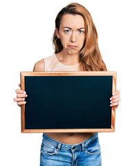 Young caucasian woman holding blackboard depressed and worry for distress, crying angry and afraid. sad expression.
