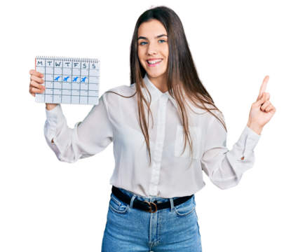 Young brunette teenager holding travel calendar smiling happy pointing with hand and finger to the side