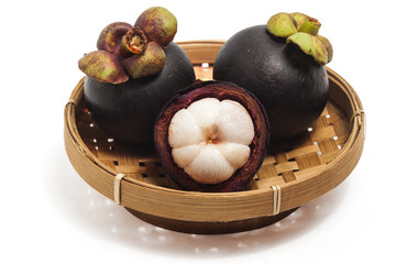 Half cut sliced and two whole fresh organic mangosteen delicious fruit in a bamboo basket plate isolated on white background clipping path