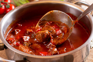 Saucepan with goulash meat, a soup or stew of meat and vegetables seasoned with paprika and spices. Perfect for recipe, article, menu book, or any cooking contents.