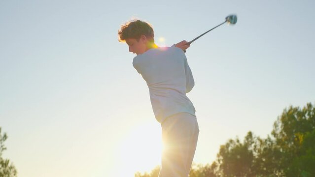 Golf game a golfer hits the ball in the sunlight. People, sport, leisure activity, recreation and lifestyle, man hitting ball with club in golf course