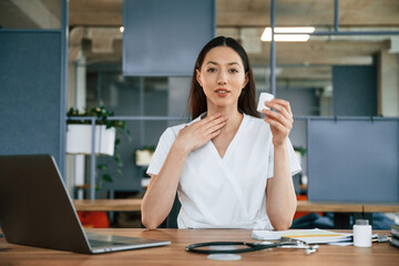 Professional practitioner. Female doctor in white coat is indoors
