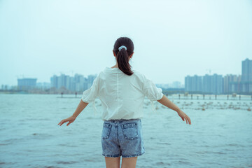 A young girl is standing by the lake