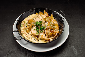 A dish of baked potatoes in the peasant style with bacon and sauce