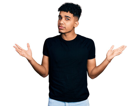 Young african american man wearing casual black t shirt clueless and confused with open arms, no idea and doubtful face.
