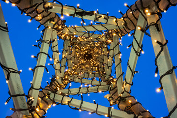 Looking up inside an antique metal post made of steel elements. The beams are wrapped in wires, the...