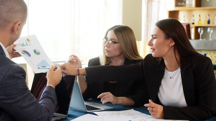 Close-up group of people talking in budget plan report with brief presentation of chart data in...