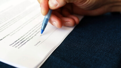 Close-up of a businessman putting his signature on a business agreement document. A man signs an agreement on paper. Business and resources concept.