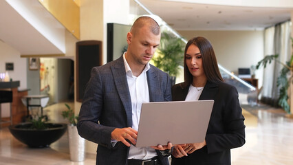 Confident male leader negotiating with business woman, explaining the benefits of a contract in the lobby, advising a corporate client presenting a business proposal.