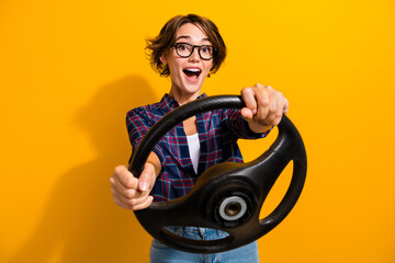 Fototapeta na wymiar Photo of funky overjoyed woman dressed plaid shirt in eyewear hold steering wheel driving vehicle isolated on yellow color background