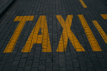 Yellow taxi sign on the cobblestones in the center of the old town. Belgrade, Serbia. Letter...