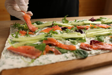 Salmon and cucumbers are added to lavash with cheese and greens. Preparation of a roll with cheese,...