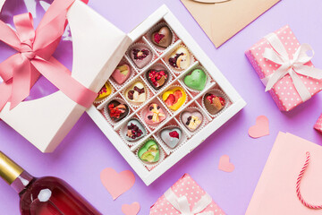 top view photo of st valentine day decor shopping, bag, wine, bottle, envelope, gift, box, candy and red heart on colored background with empty space. Frame background