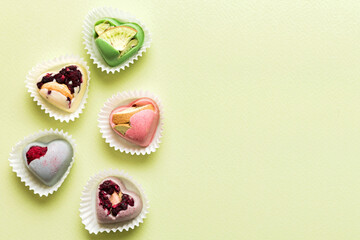 chocolate sweets in the form of a heart with fruits and nuts on a colored background. top view with space for text, holiday concept