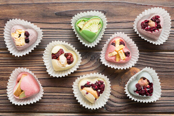 chocolate sweets in the form of a heart with fruits and nuts on a colored background. top view with space for text, holiday concept