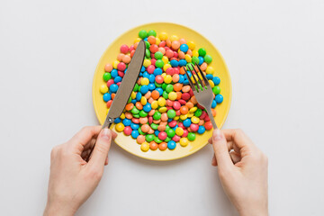the girl holds cutlery in her hands and eats sweets in a plate. Health and obesity concept, top...