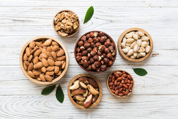 mixed nuts in wooden bowl. Mix of various nuts on colored background. pistachios, cashews, walnuts, hazelnuts, peanuts and brazil nuts