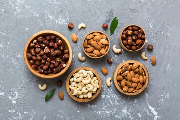 Assortment of nuts in wooden bowl on colored table. Cashew, hazelnuts, walnuts, almonds. Mix of nuts Top view with copy space