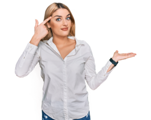 Young caucasian woman wearing casual clothes confused and annoyed with open palm showing copy space and pointing finger to forehead. think about it.