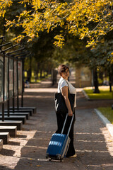 A middle-aged woman walks along the boulevard with a suitcase