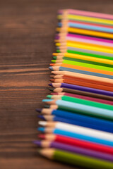 Obraz premium Set of watercolor pencils on brown wooden. Side view, selective focus