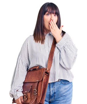 Young plus size woman wearing leather bag covering mouth with hand, shocked and afraid for mistake. surprised expression
