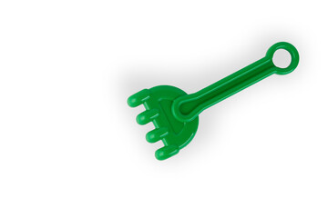 Green plastic rake to play in sandbox isolated on white.