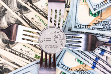 A new metal coin of the Russian ruble, with a denomination of one ruble against the background of American banknotes and metal forks. Crisis in Russia. - obrazy, fototapety, plakaty