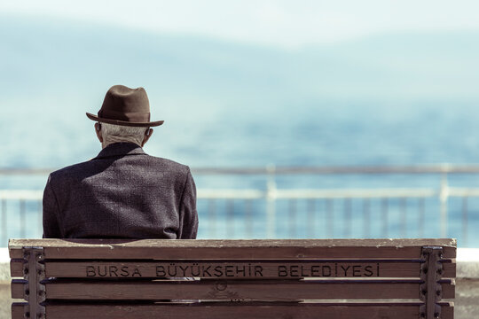 Bursa, Turkey - 27 April 2023: View of an old man sitting on a bench along the coastline.