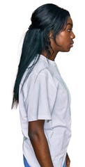 Young african american woman wearing casual white t shirt looking to side, relax profile pose with natural face with confident smile.