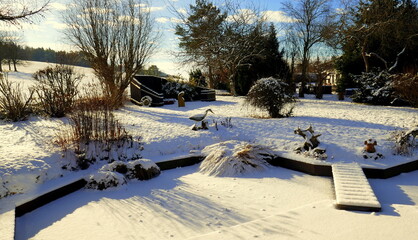 sonnige, winterliche Gartenanlage mit Teich an Terrasse angrenzend