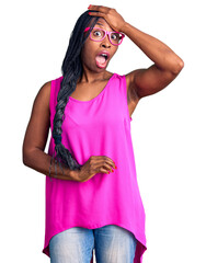Young african american woman wearing casual clothes and glasses surprised with hand on head for...