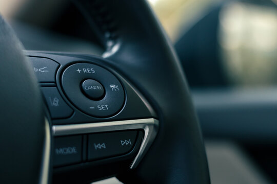 steering wheel buttons for cruise control functions, automatic speed limiter in modern car, shallow depth of field