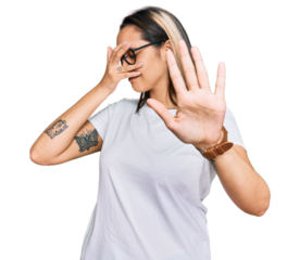 Young hispanic woman wearing casual white t shirt covering eyes with hands and doing stop gesture with sad and fear expression. embarrassed and negative concept.