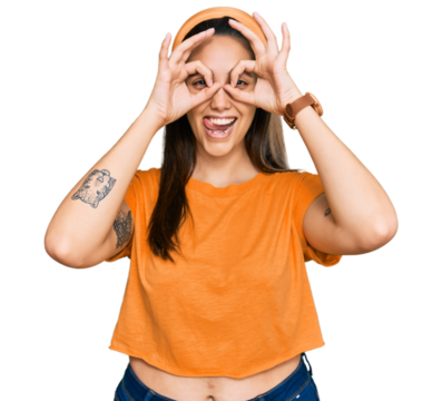 Young hispanic woman wearing casual clothes doing ok gesture like binoculars sticking tongue out, eyes looking through fingers. crazy expression.