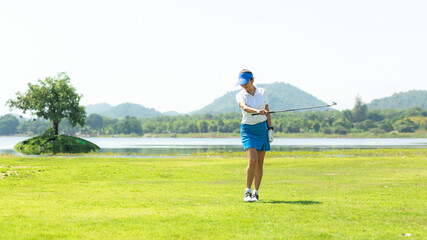 Naklejka premium Golfer sport course golf ball fairway. People lifestyle woman relax after swing golf ball on the green. Asia female player game shot in summer. Healthy and Sport outdoor, copy space for text