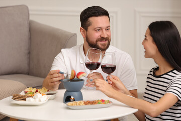 Affectionate couple enjoying chocolate fondue during romantic date at home