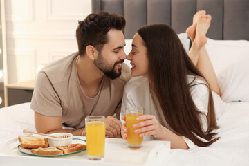 Obraz na płótnie Canvas Happy couple having breakfast on bed at home