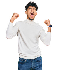 Fototapeta premium Young arab man wearing casual winter sweater angry and mad screaming frustrated and furious, shouting with anger. rage and aggressive concept.