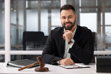Portrait of smiling lawyer at table in office - obrazy, fototapety, plakaty