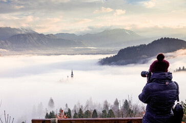 photographer woman taking pictures of amazing sunrise at lake Bled from Ojstrica viewpoint,...