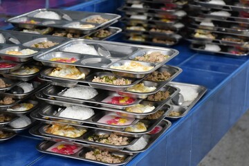 Various foods on stainless steel trays are arranged neatly on top of each other.