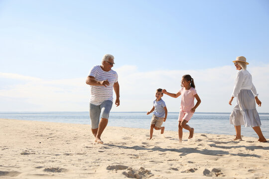 Cute little children with grandparents spending time together on sea beach