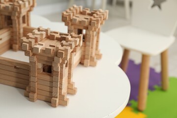 Fototapeta na wymiar Wooden fortress on white table indoors, space for text. Children's toy