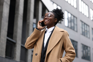 Happy woman talking on smartphone outdoors. Lawyer, businesswoman, accountant or manager