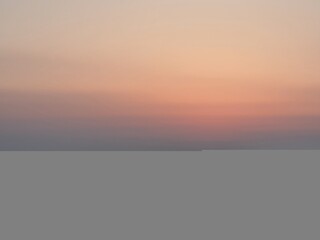 
A vibrant sunset over the ocean, with the sun setting on the horizon. The sky transitions from...