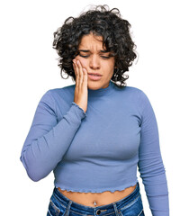 Young hispanic woman with curly hair wearing casual clothes touching mouth with hand with painful expression because of toothache or dental illness on teeth. dentist