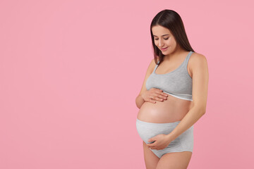 Beautiful pregnant woman in comfortable maternity underwear on pink background, space for text